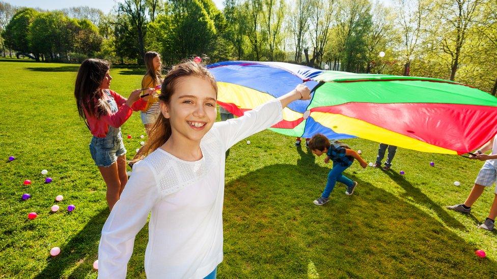 Kids playing parchute games in field.