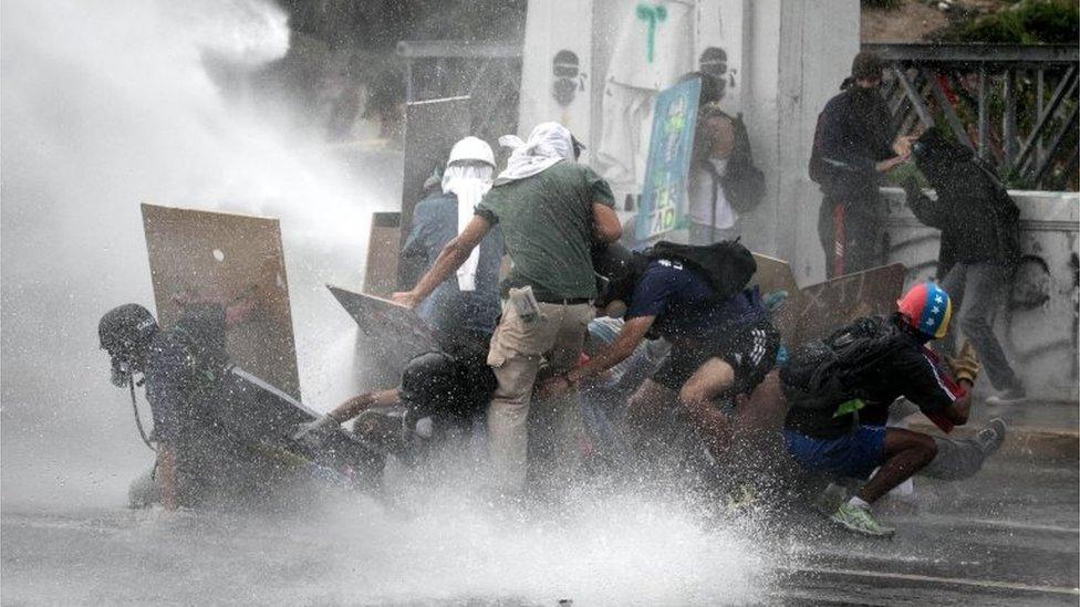 Protesters react as they get hit by water jets during a protest in Caracas, Venezuela, 07 June 2017.