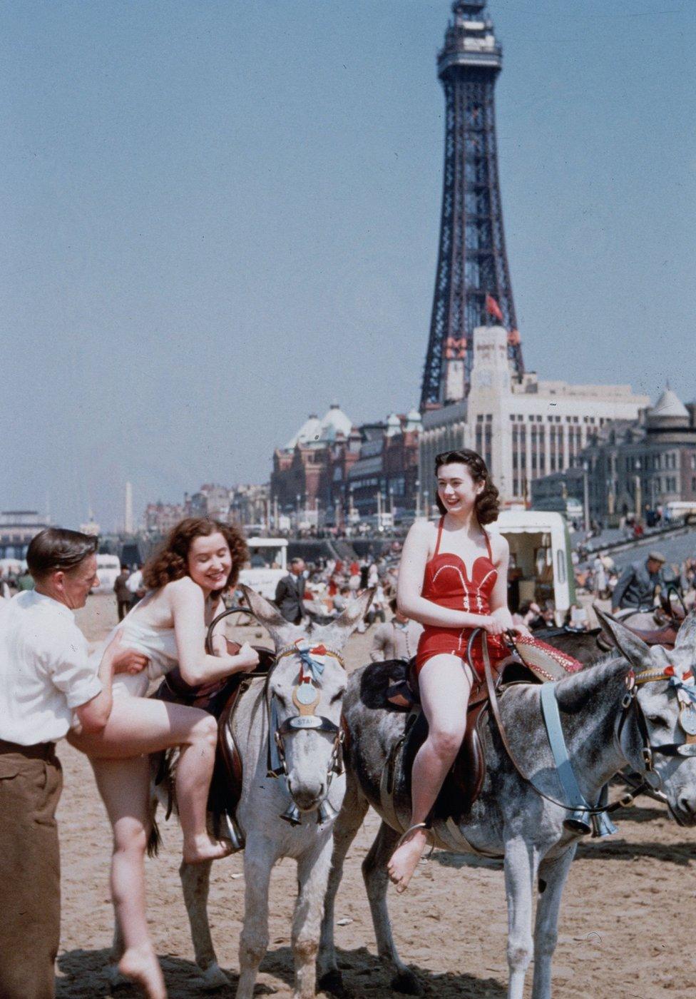 Holiday-makers riding donkeys on the beach at Blackpool