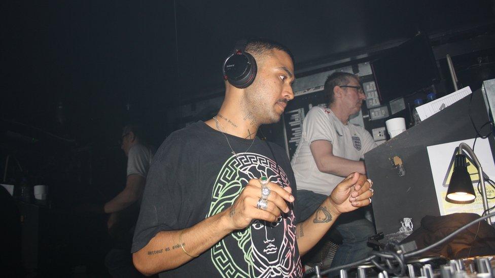 A man behind a desk wearing headphones.