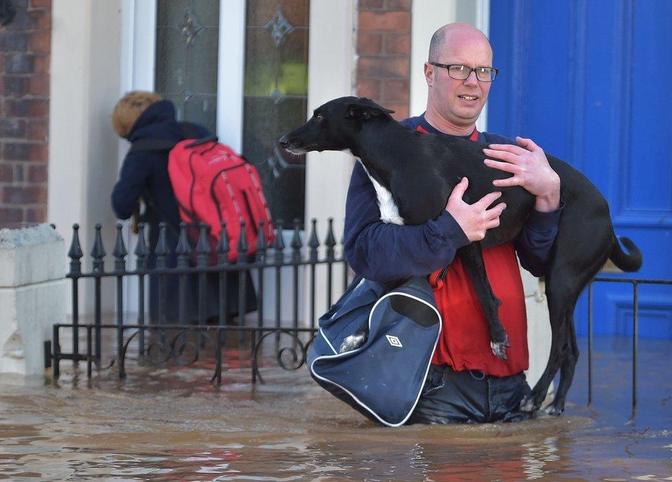 Residents leave their home in Carlisle which was among the worst-hit areas over the weekend