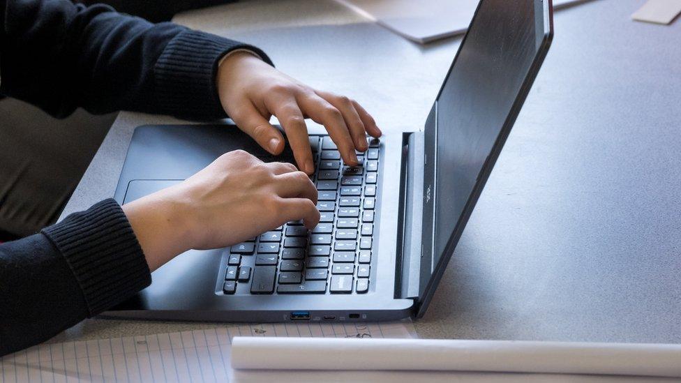 A student typing on a laptop