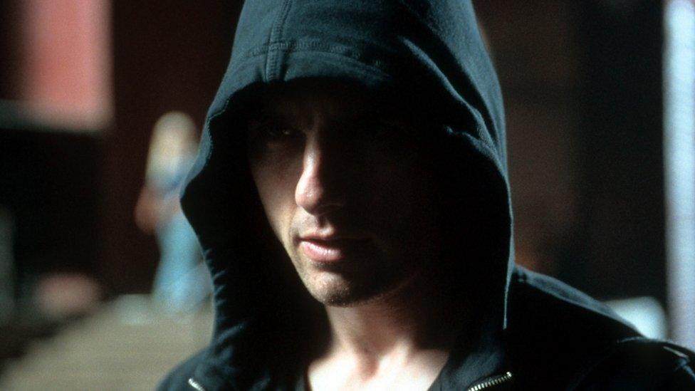 Tom Cruise glowers from beneath a black hoodie in this still from the film Minority Report