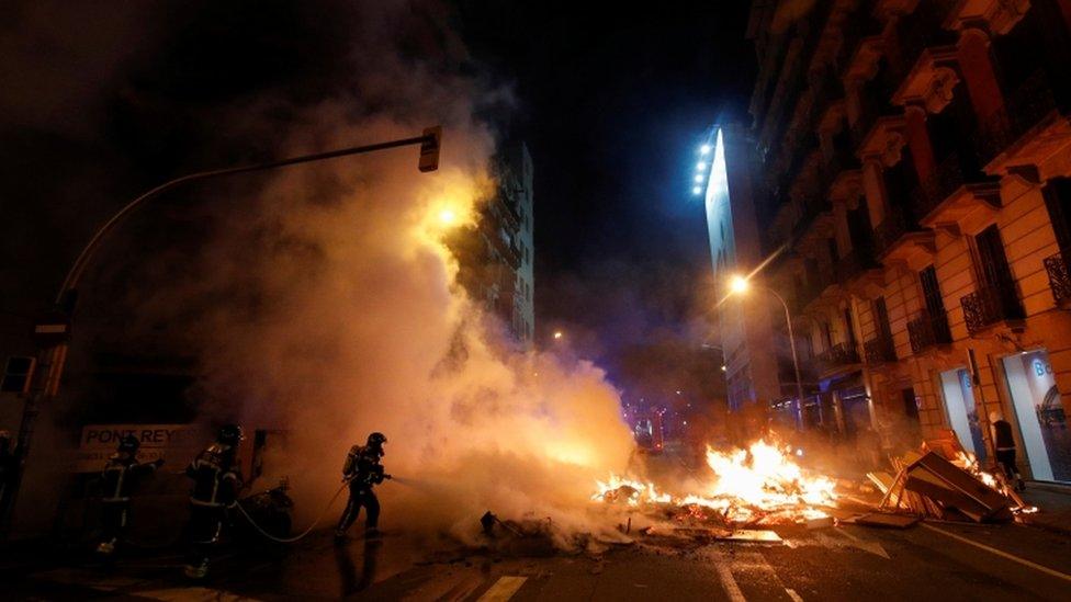 Firefighters work to extinguish a fire during a protest against the arrest of Catalan rapper Pablo Hasél in Barcelona, Spain