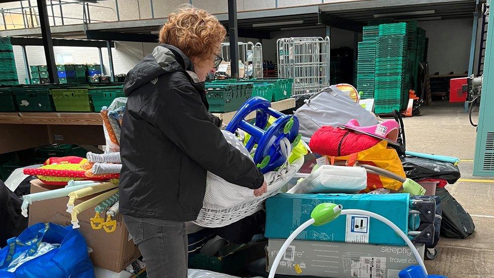 A person moving items at a baby bank in Bedford