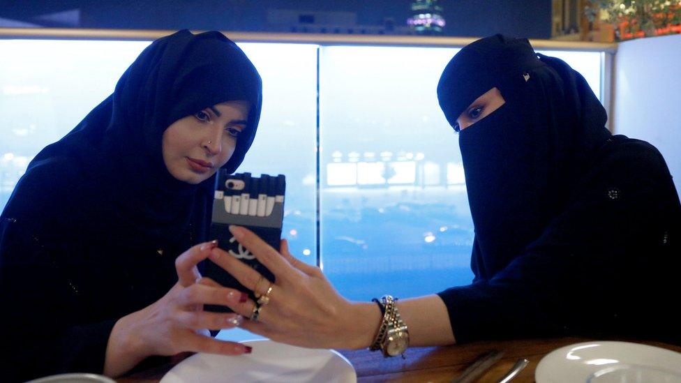 Two women looking at a mobile phone in a cafe in Saudi Arabia