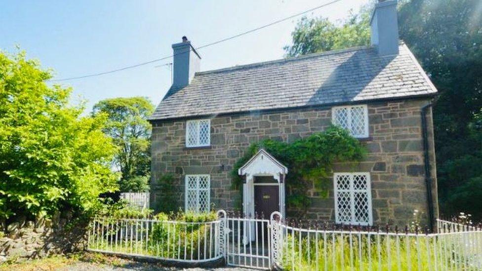 Angela's cottage in north Powys. The sun is shining and it's surrounded by greenery.