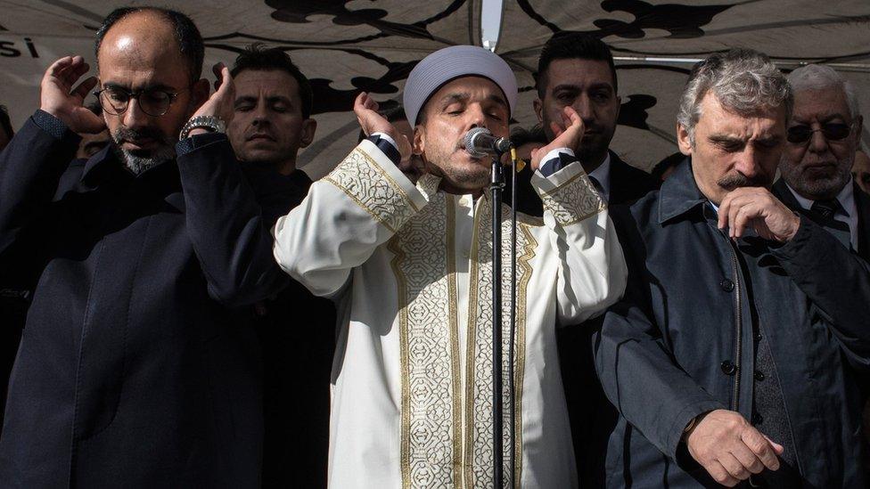 An imam recites verses from the Koran under a tent set up to protect against the rain in Istanbul