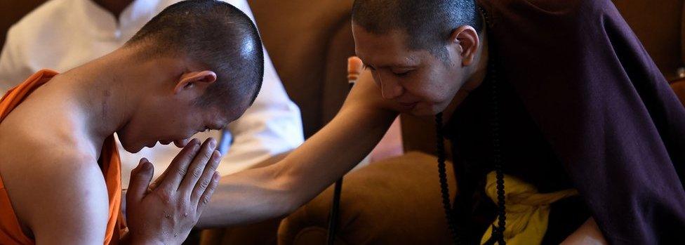 Thai football coach Ekkapol Chantawong (L), who will remain a monk until the end of Buddhist Lent, pays his respects during a ceremony to mark the end of the retreat of 11 members of the "Wild Boars" football team as novice monks at the Wat Phra That Doi Tung temple