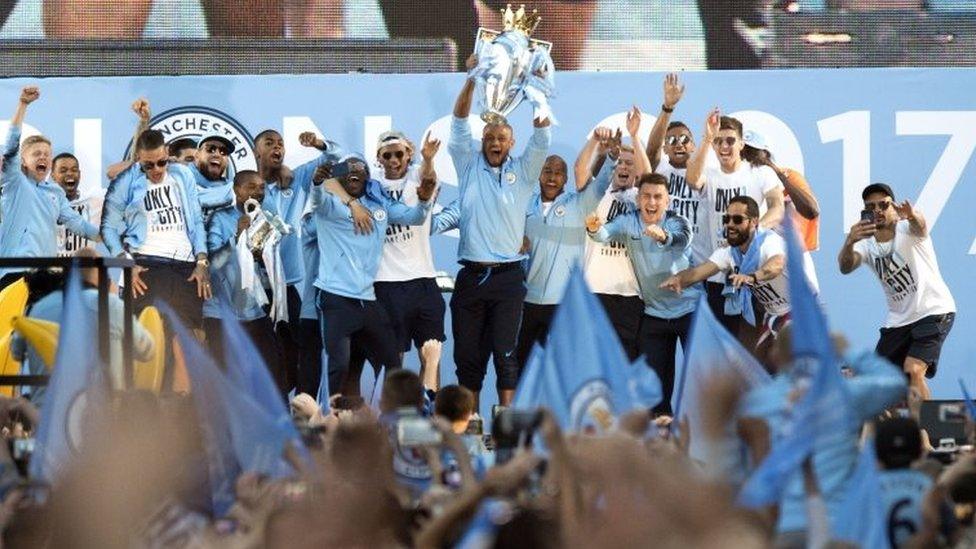 Manchester City players lift the trophies on stage during the Premier League champions trophy parade