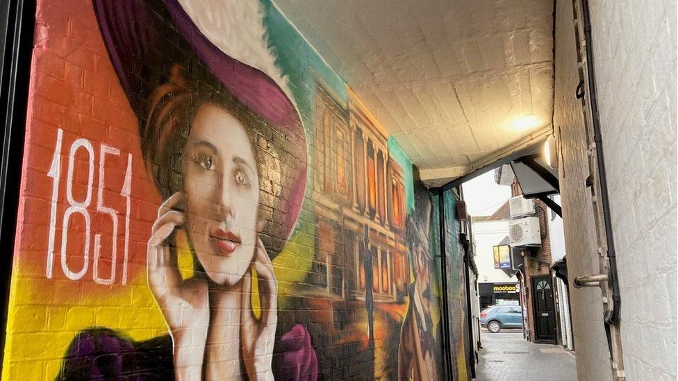 The colourful mural, featuring the date 1851 and a Victorian woman's face, in an alleyway