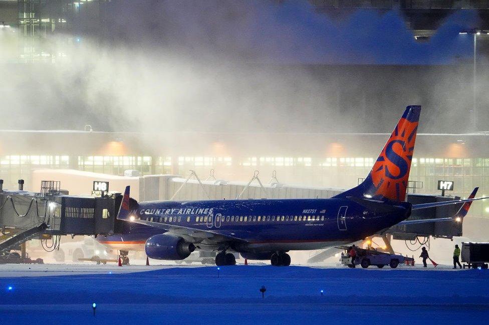 High winds whip around 7.5 inches of new snow at Minneapolis-St. Paul International Airport as workers prepare a Sun Country Airlines plane for take-off Thursday, December. 22, 2022.