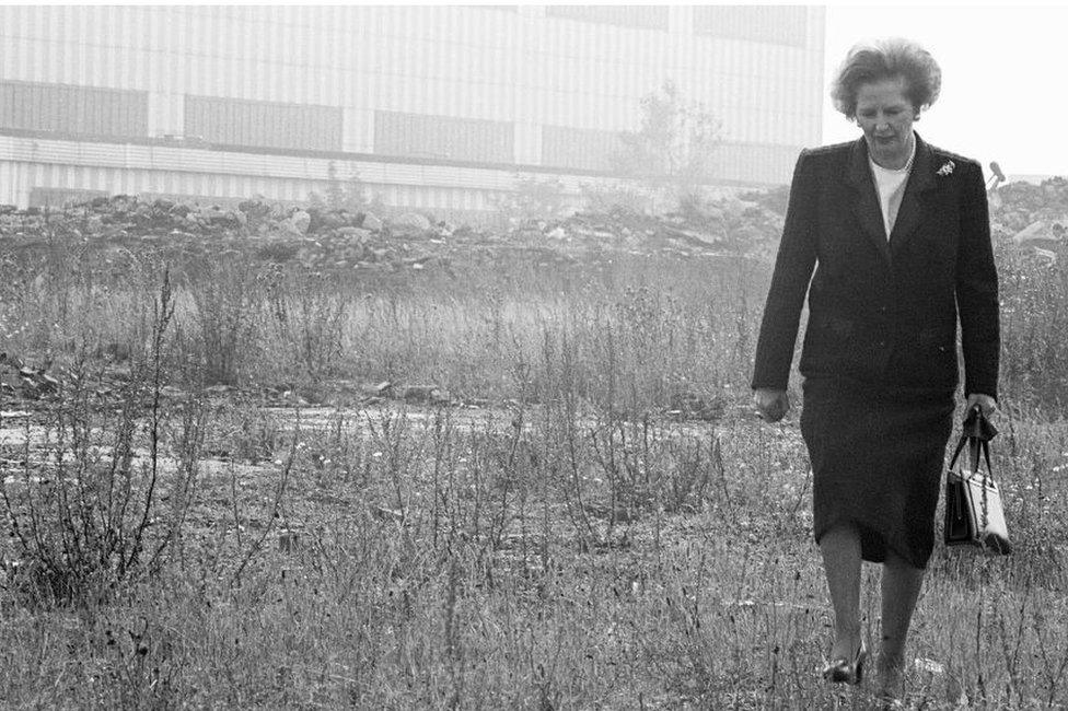 Margaret Thatcher walking through a derelict site