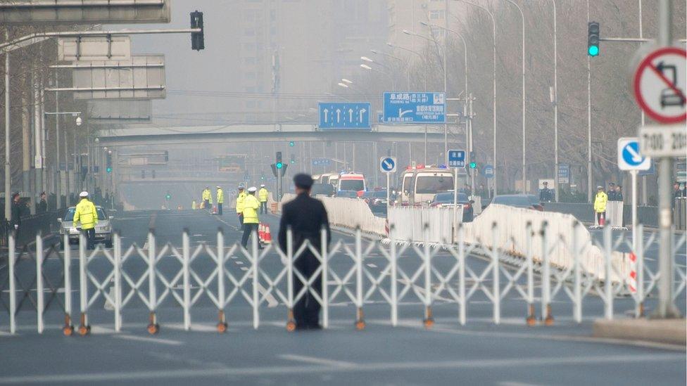 Chinese policemen block a road as a procession believed to be North Korean officials pass near Diaoyutai State Guesthouse in Beijing