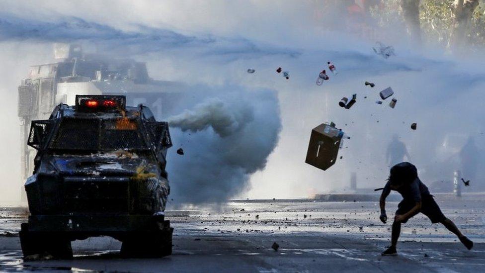 A demonstrator throws items at an armoured vehicle during a protest against Chile"s government in Santiago, Chile December 30, 2019.