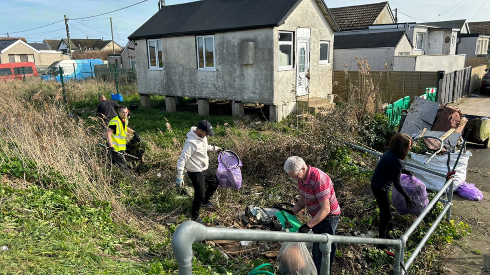 Litter pickers cleaning a grass area