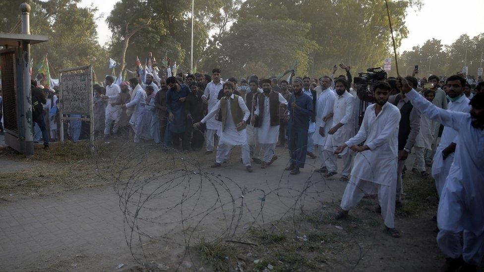 Protestors react after police fired tear gas shells to stop them reaching the French embassy in Islamabad