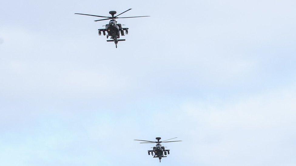 Two Apache helicopters flying in the air