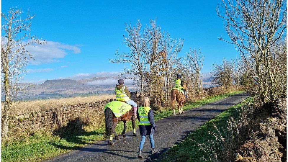 Mounted volunteers on a narrow road