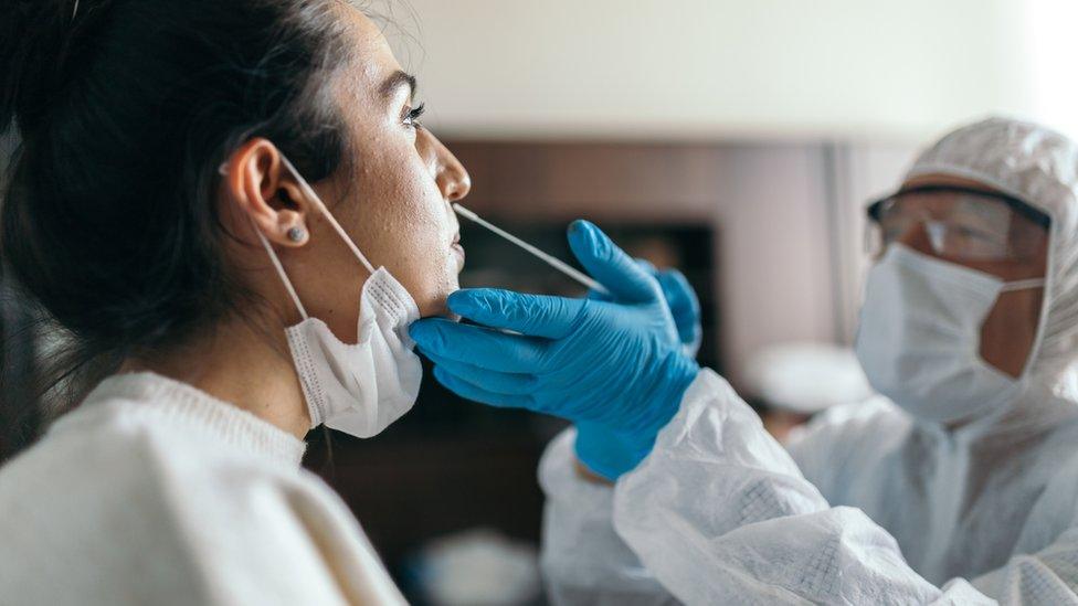 Doctor in protective workwear taking nose swab test from young woman (generic)