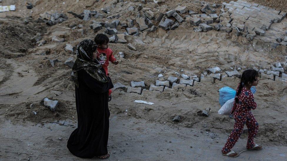 People walk at damaged street after Israel's warplanes carried out airstrikes in Gaza City, Gaza on May 20, 2021.