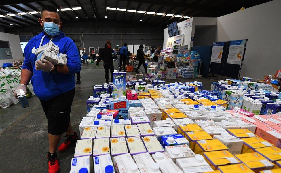 A volunteer helps organise donated food supplies