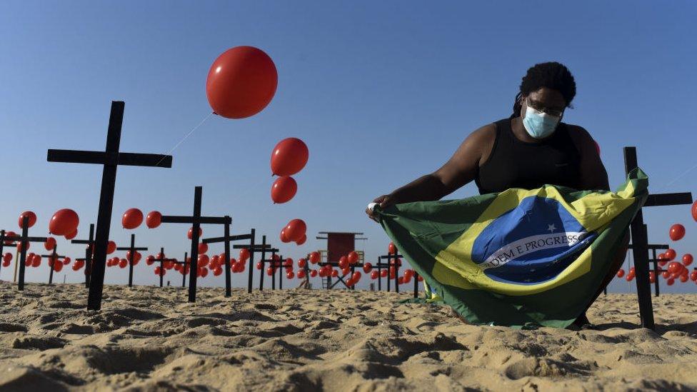 A man holds Brazilian flag between red balloons in Rio de Janeiro