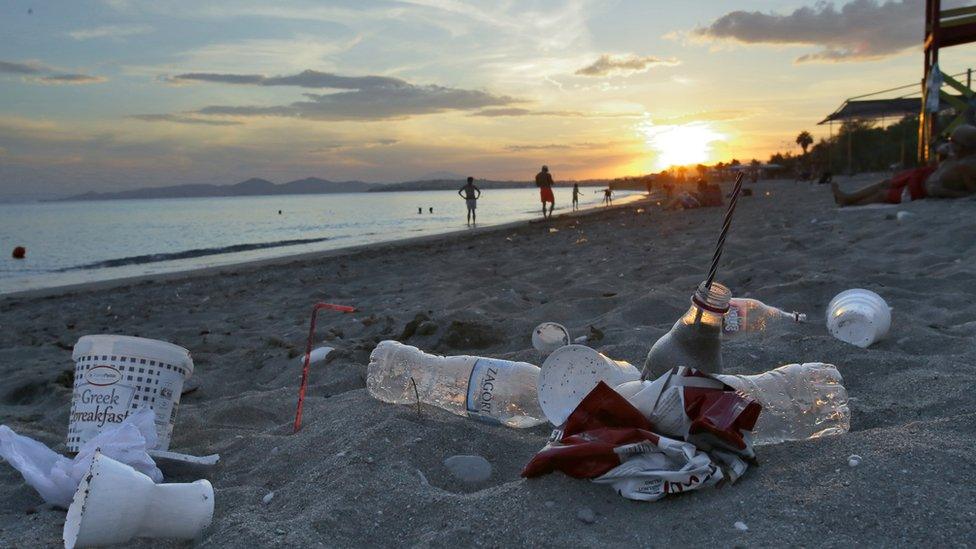 Plastic cups used by tourists on the Aegean sea beach near Athens, Greece