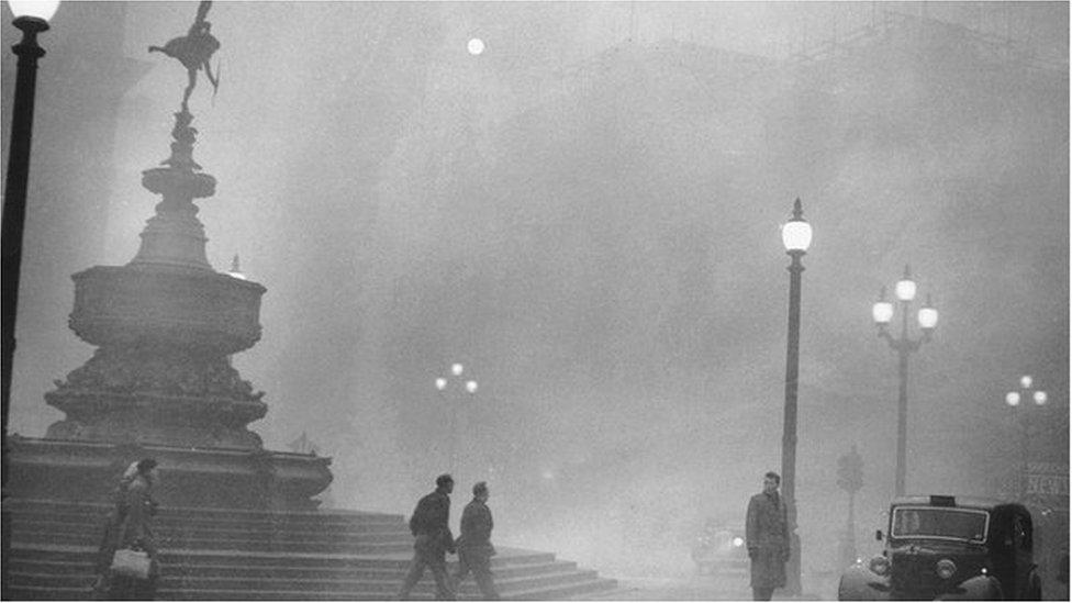 Pedestrians struggle to see through the dense fog in Piccadilly