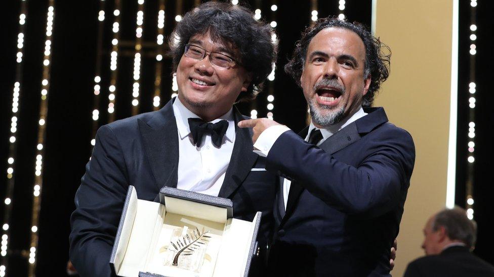 South Korean director Bong Joon-Ho (L) poses on stage with Mexican director and President of the Jury of the Cannes Film Festival Alejandro Gonzalez Inarritu after he was awarded with the Palme d"Or for the film "Parasite" on May 25, 2019