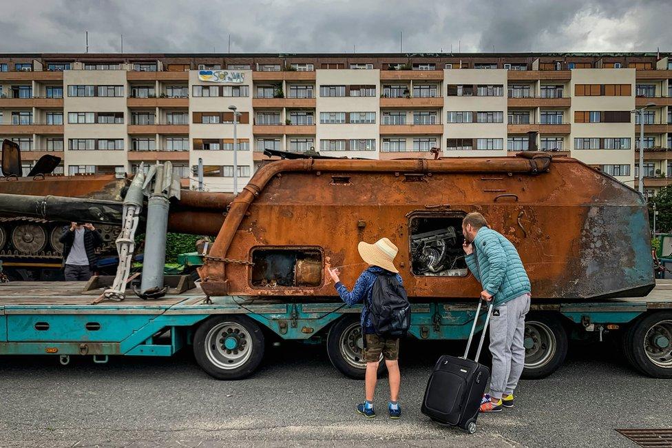 A man with a child looks at a Russian military equipment which was destroyed in fights with the Ukrainian army, placed for exhibition on a truck, in Prague, Czech Republic, on 10 July 2022