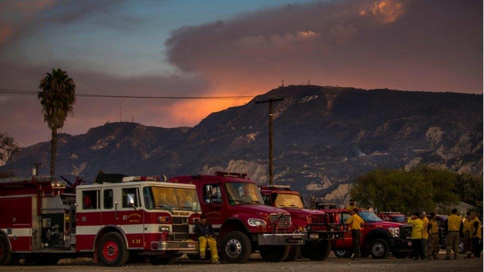 Firefghters take a break at the end of the day in front of the scorched mountain in Santa Paula, Ventura County, California in November