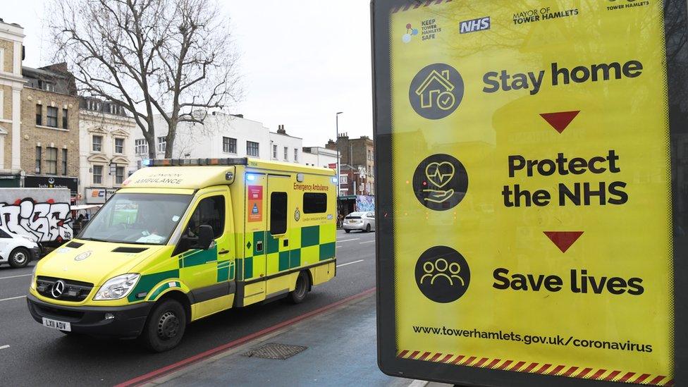 Ambulance driving past Covid information sign in London in January 2021