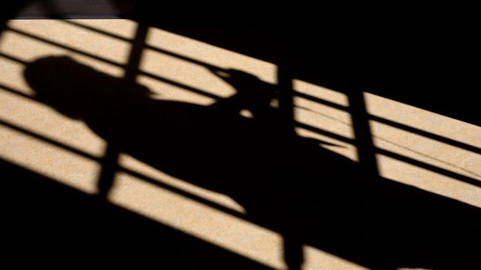 Shadow of prison officer across cell bars at HMP Berwyn jail in Wrexham, Wales