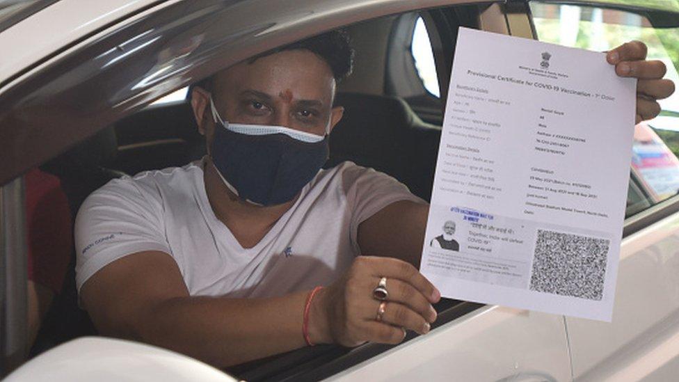 An Indian man shows his vaccine certificate