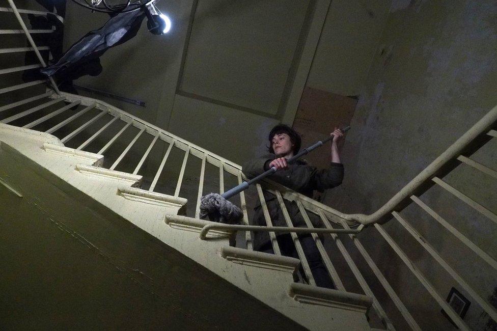 A woman cleaning a staircase with a mop