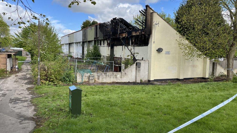 A police cordon around a burnt building and it has lost its roof.