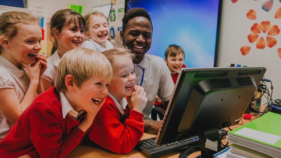 teacher-with-kids-laughing-at-computer-screen.