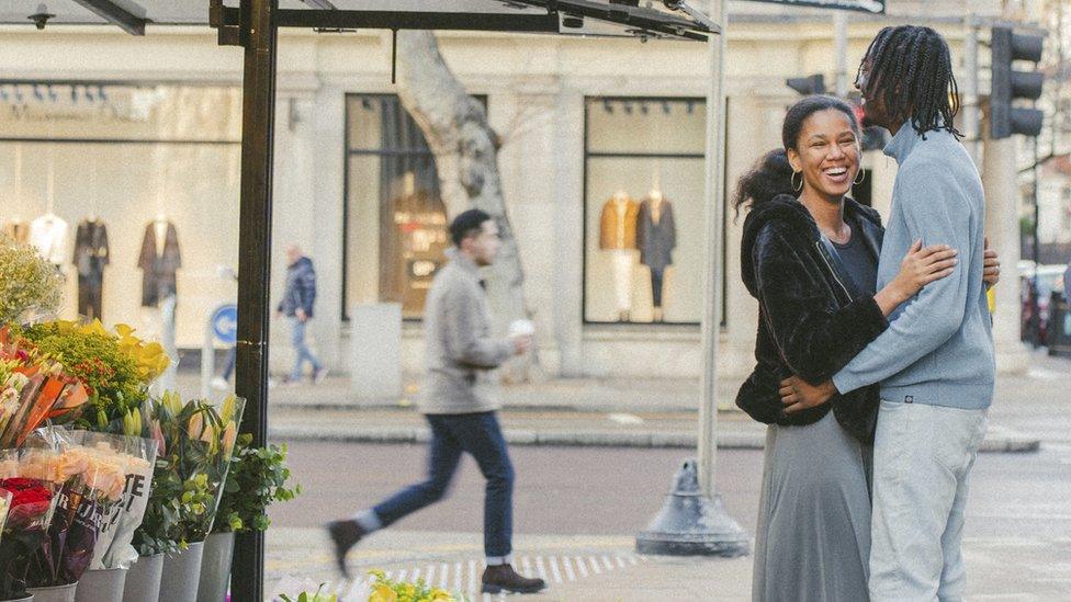 A couple embracing beside a florist's stall on the corner of Wright's Lane and Kensington High Street