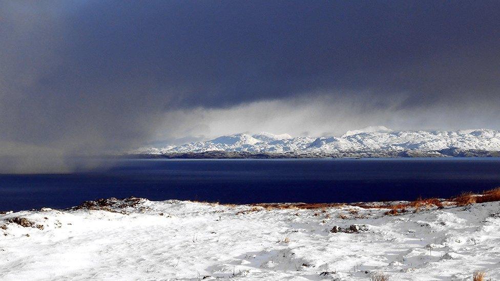 Dark clouds over the sea with snow lying on the surrounding ground