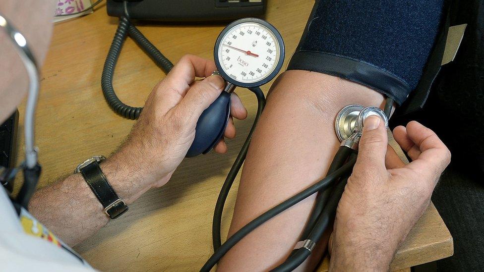 File image of GP checking a patient's blood pressure on their arm