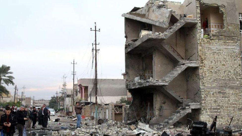 Iraqis stand at the site of a car bomb attack in eastern Baghdad (12 January 2016)