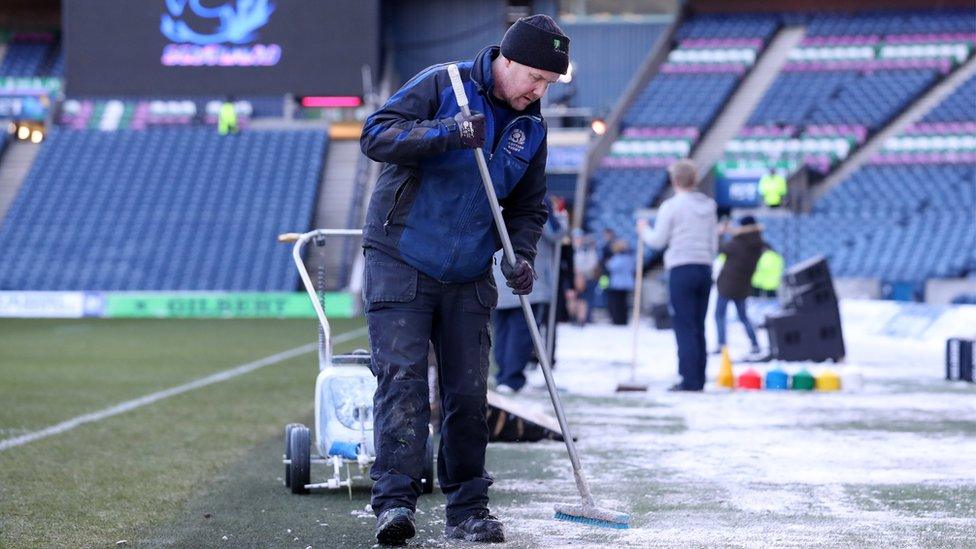 Ground staff clear the Murrayfield pitch after snowfall in Edinburgh