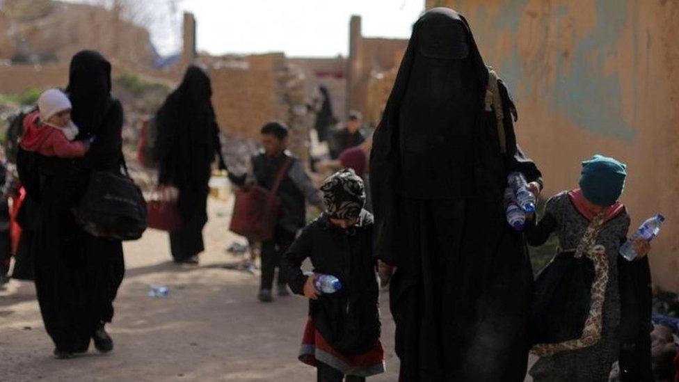 Families of Islamic State fighters walk as they surrendered in the village of Baghuz,in Syria on 12 March 2019