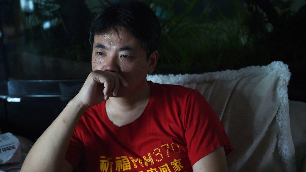 Jiang Hui, whose mother was on flight MH370, watches a TV news bulletin about the plane at his Beijing home in 2015