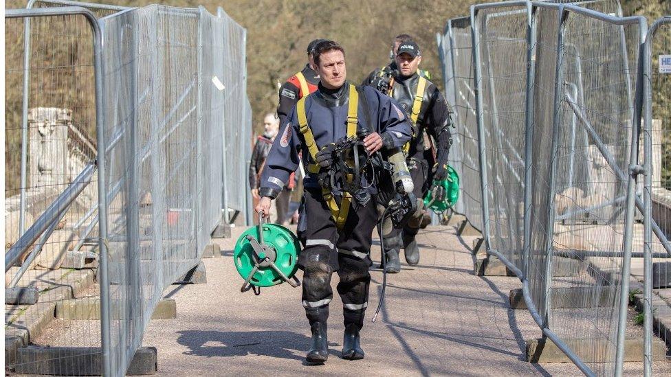 Police divers walk across the bridge