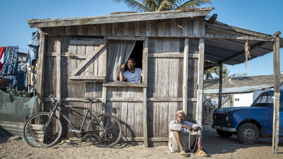 An man sits outside his home while chanting on prayer beads in Fort Dauphin, Madagascar