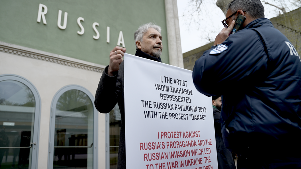 Russian artist Vadim Zakharov holds up a placard distancing himself from his own country's invasion of Ukraine