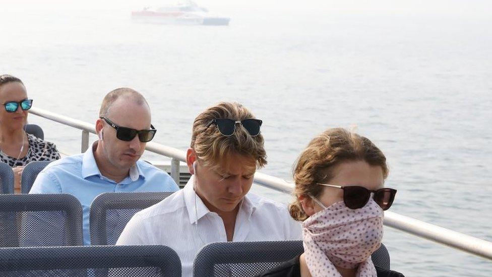 A ferry in smoke-hit Sydney, with one commuter wearing a face mask