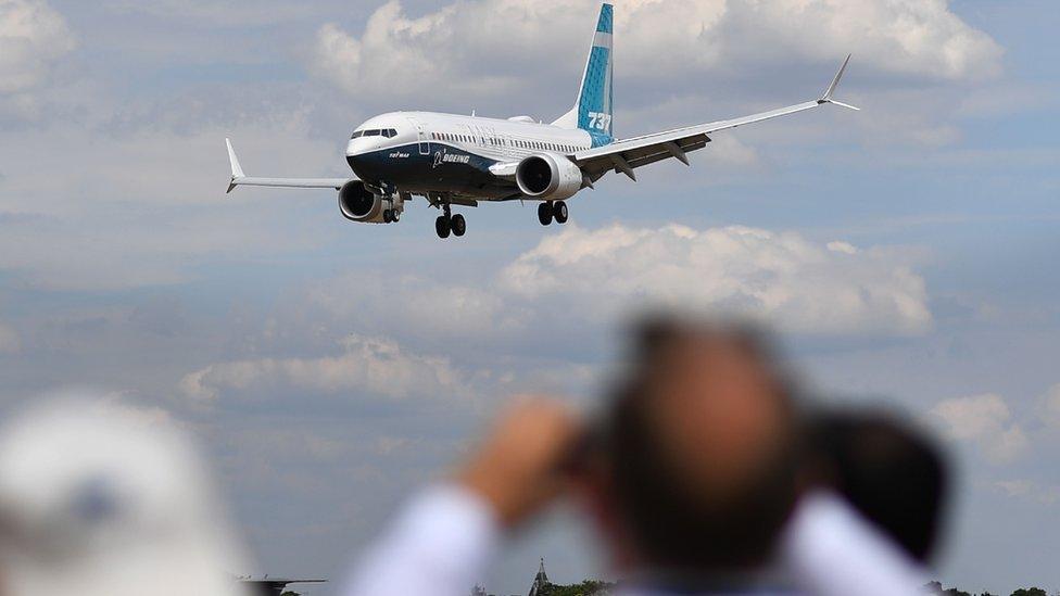 Visitors watch as a Boeing 737 Max lands after an air display during the Farnborough Airshow, south west of London, on July 16, 2018.